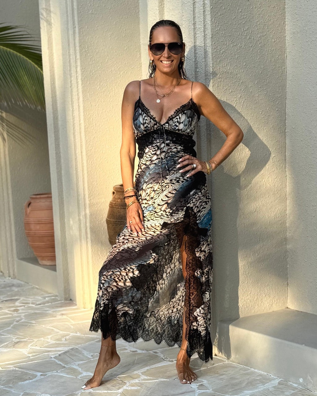 Woman in a stylish dress standing against a light-colored wall with decorative elements.